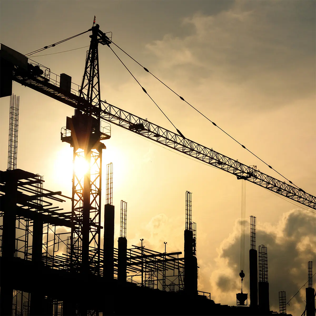 A large-scale construction site with cranes, scaffolding, and concrete structures in progress. Steel reinforcements and building materials are arranged, showcasing the industrial construction process. Prime Edge Technical Services LLC ensures precise construction survey solutions for efficient project execution.