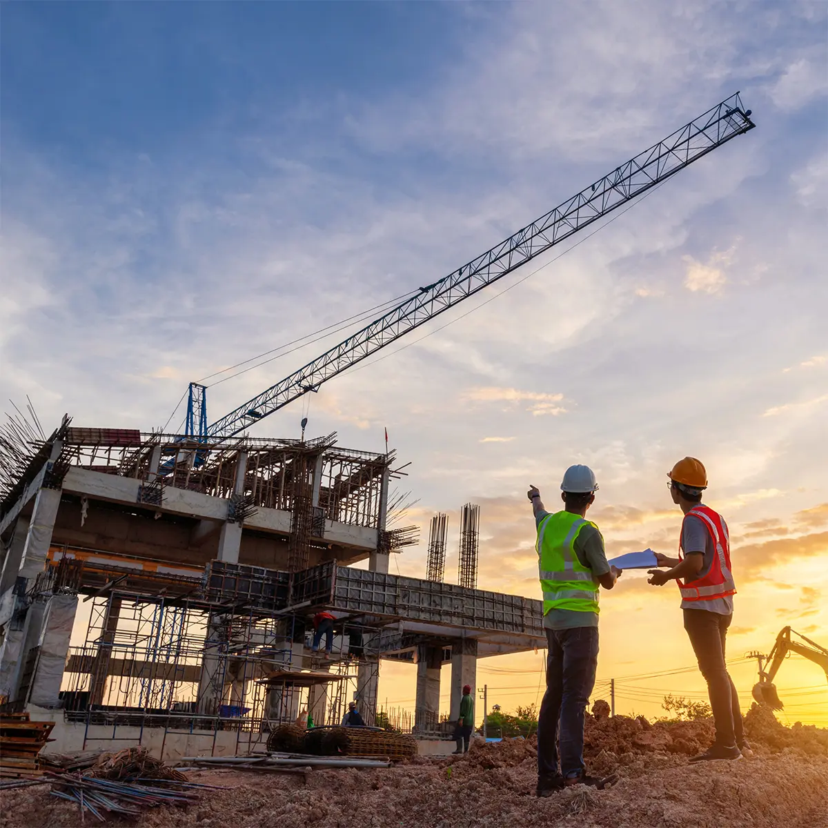 Engineers from Prime Edge Technical Services LLC conduct a Construction Survey at an active building site during sunset. Wearing safety gear and high-visibility vests, they assess the progress of a multi-story structure with cranes and scaffolding in the background.